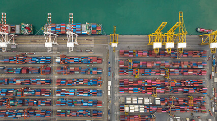 container ship and commercial dock load and unloading cargo from container ship import and export by crane for distributing goods by trailers transportation, aerial top view