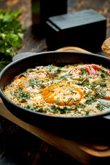 Fried eggs with tomatoes, onions and pita bread in a pan on a wooden background. Tasty Shakshuka