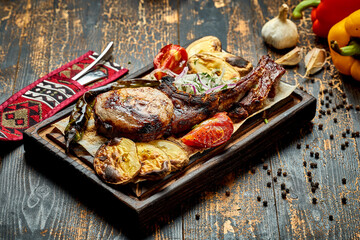 Pork steak on the bone, barbecued with vegetables on a wooden board.