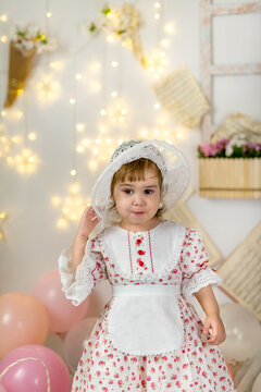 A little beautiful girl in a doll dress and a hat