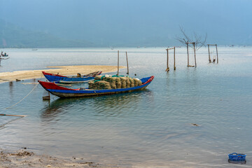 Naklejka premium Vietnam, rainy and cloudy day at the Lap An Lagoon. Fisher boats for oyster farming. 