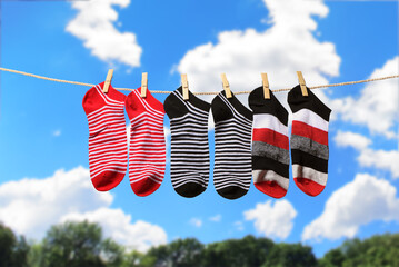 Clean washed striped socks hanging on clothesline to dry outdoors on sunny summer day. Clothesline...