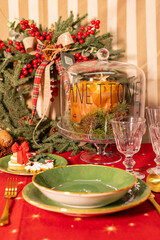 Set natalizio con panettone, piatti in ceramica verdi, bicchieri di cristallo, posate in acciaio e tovaglia rossa