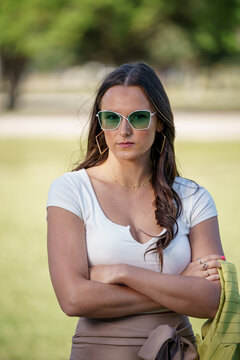 Flash photo of a woman posing with arms crossed and green sunglasses