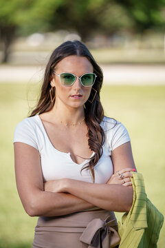 Flash photo of a woman posing with arms crossed and green sunglasses