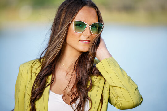 Retractive young female model posing in green tinted sunglasses