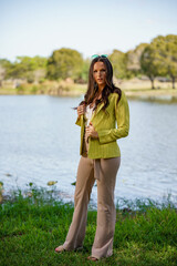 Beautiful young female model posing in a green jacket in a nature seen in the park