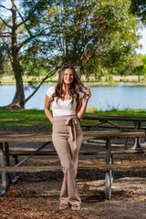 Attractive young woman smiling playing with her hair with legs crossed in a park setting