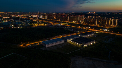 Fototapeta na wymiar Aerial view of the high-rise buildings next to bigger highway with many cars and forest in the historical and at same time modern city of St. Petersburg at summer night