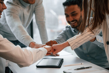 Obraz premium Knocking the fists. Four people are working in the office together