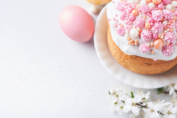 Obraz na płótnie Canvas Traditional Easter sweet bread or cakes with white icing and sugar decor, colored eggs and cherry blossom tree branch over white table. Various Spring Easter cakes. Happy Easter day. Selective focus.