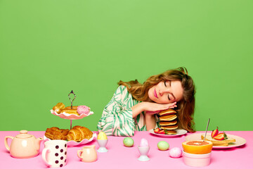 Obraz na płótnie Canvas One beautiful young girl folded hands together and sleeping at table with products over green background. Colorful eggs on table