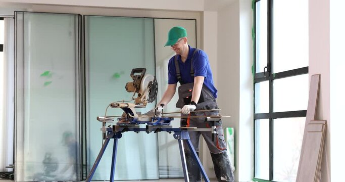 Male builder in protective overalls cutting plank with circular saw 4k movie slow motion