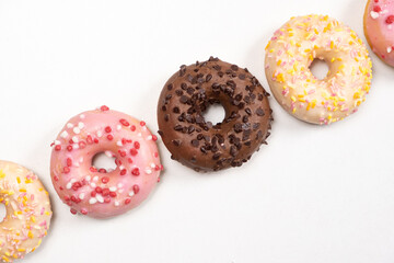 Five donuts in a row - white, pink and chocolate on a white background top view