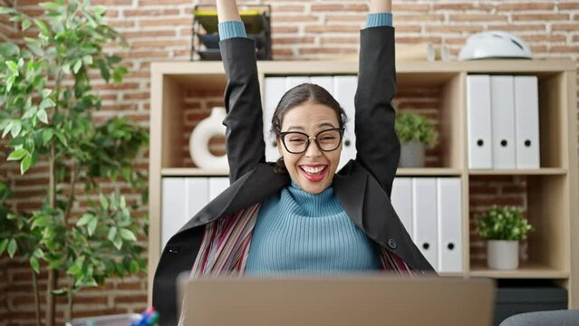 Young beautiful hispanic woman business worker using laptop celebrating at office