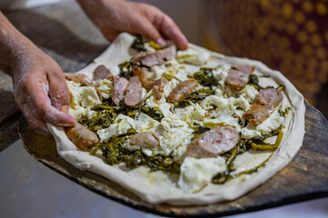 Pizza tradizionale napoletana a ruota di carro condita con salsiccia, friarielli e mozzarella di...