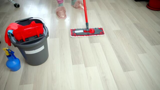 woman cleaning floor with wet mop 	
