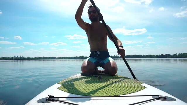 Strong man swims while surfing beside boat
