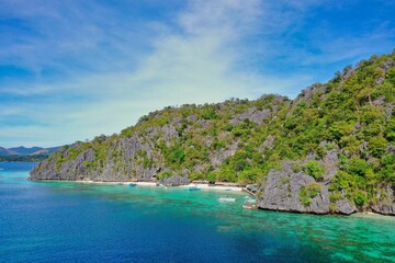 Fototapeta na wymiar Panorama drone shot of majestic rocks in Coron, Palawan in the Philippines, covered with bushes and surrounded by the sea.
