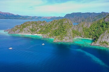 Fototapeta premium Panorama drone shot of majestic rocks in Coron, Palawan in the Philippines, covered with bushes and surrounded by the sea.