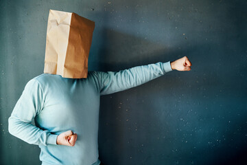 Side view of man with a paper bag on head with clenched fists in fighting stance, practicing karate...