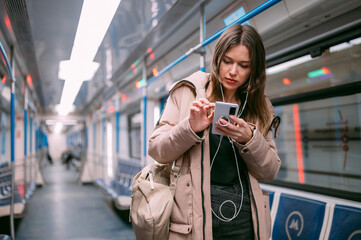 A young woman rides in a modern subway car with a phone in her hands