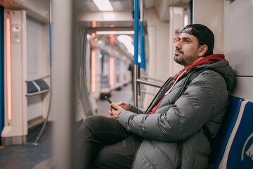 A young man rides standing in a modern subway car.