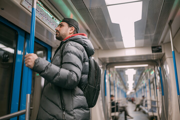Fototapeta na wymiar A young man rides standing in a modern subway car.