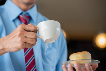 engineer with blue helmet and shirt hurry urgency urgency donut fast food and coffee at lunch meal time. Worker busy hurry bite donut junk fast food in working site.
