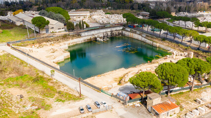 Fototapeta na wymiar Aerial view of a marble factory built near a natural lake with spring water. There is no one and the pond and the industry are empty.