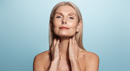 Elegant elderly woman, aging model, washing her face, rubbing nourishing skin lifting mask, using...