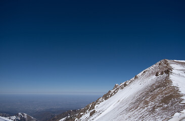 Snow covered mountain slope with deep blue sky 