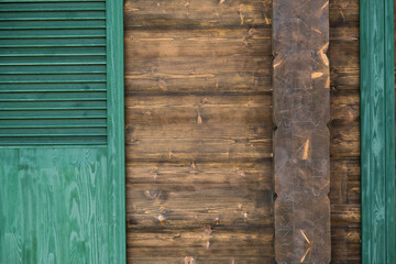 Green wooden shutters as a detail of the wooden house