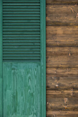 Green wooden shutters as a detail of the wooden house