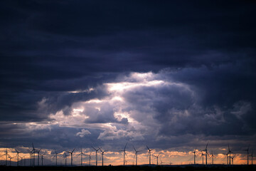 Fototapeta na wymiar Dark Clouds In Sunset over Windmills In a field In Austria