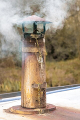 Vertical closeup of smoke coming out of a boat chimney along the Thrupp Canal in Oxfordshire, UK