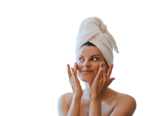 Young adult hispanic woman at bathroom with towel wrapped on head applying cream on face satisfied by spa procedure. Relaxed American female trying new skin care lotion against transparent background