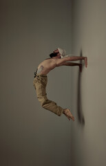 Flying bridge. Male sportsman training shirtless, doing flexible yoga exercises over studio background. Muscular body shape. Art of movement, male body aesthetics, health, sportive lifestyle concept