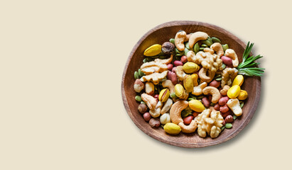 Nuts mix in a wooden bowl on a yellow background. The concept of vegetarian and diet snacks.