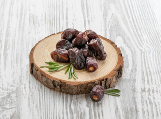 Dry fruits dates in a wooden board  on a white wooden background. Rustic style. The concept of vegetarian and diet snacks.