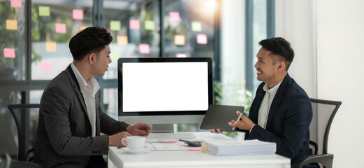 Two business people talk project strategy at office meeting room. Businessman discuss project planning with colleague at modern workplace while having conversation and advice on financial data report.