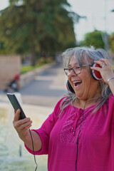 white-haired woman making a video call with her cell phone