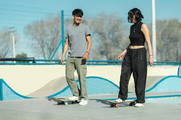 Couple of skate boarders talking and laughing while riding in the skate park