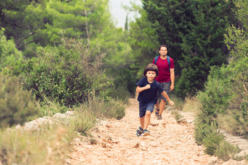 Naklejka premium Father and Little Son Walking in the Wood Together