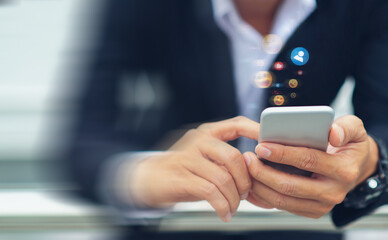 Close-up of a businessman using his smartphone, hands holding it and typing while the action is blurred to communicate with people online and send emoji.