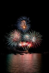 multi colored fireworks in the night sky over water on a beach