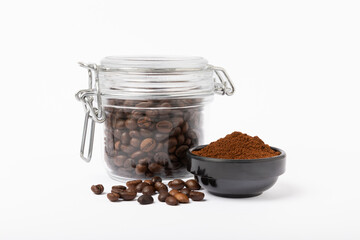 Bowl of ground coffee and glass jar with coffee beans isolated on white background.