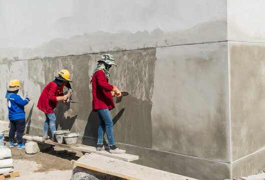 Builders are applying precast mortar to the walls of buildings to give a smooth and even finish to the walls. Plastering the building walls requires resolution and expertise in the work.