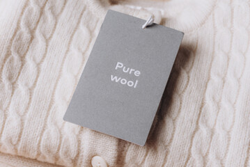 Label with Text Wool on merino wool clothes. Tag composition of clothing on knitted texture...