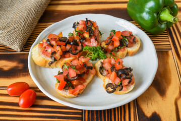 Vegetarian Bruschetta with tomatoes obasilic and olive on white plate close up